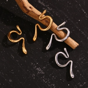 Detail shot of irregular liquid metal ear cuffs in gold and silver on black stone