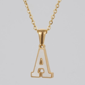 Macro detail of golden letter A pendant with white inlay on a fine cable chain