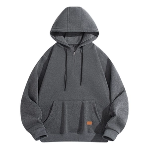 Detail of dark grey hoodie featuring brown leather patch on kangaroo pocket and M size label