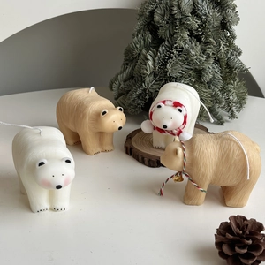 Detailed view of polar bear decorative candles with festive red scarves and pine cones