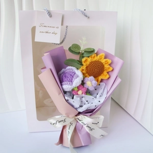 Close-up of handmade crochet sunflower and rose bouquet in a gift bag with ribbon