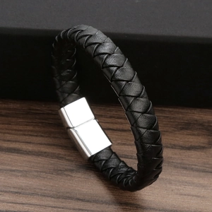 Handmade black woven leather bracelet with silver magnetic buckle on wooden background