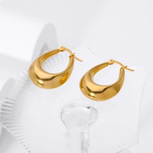 Detailed close-up of golden teardrop earrings on a textured glass surface with soft lighting