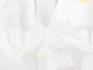 Detailed close-up of white puff sleeve dress featuring floral embroidery and mesh texture