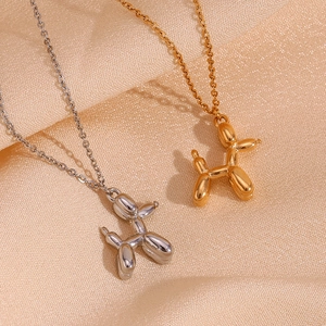 Macro shot of gold and silver balloon dog pendants with polished mirror finish on silk