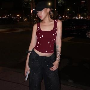 Detail of burgundy U-neck crop top featuring white bead accents in a street night setting
