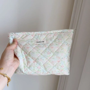 Detailed close-up of quilted floral cosmetic bag being held to show size and cotton texture