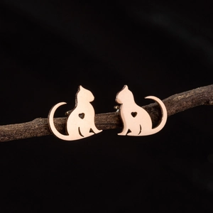 Cute rose gold cat earrings with hollow heart detail and long tail on a wood branch