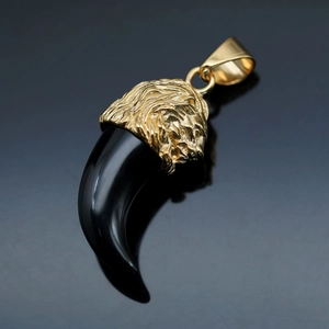 Macro shot of gold lion head relief on smooth black resin wolf tooth pendant