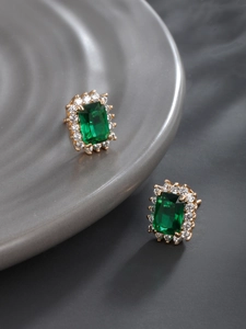 Macro detail of emerald cut gemstone earrings with a halo of clear zircon accents