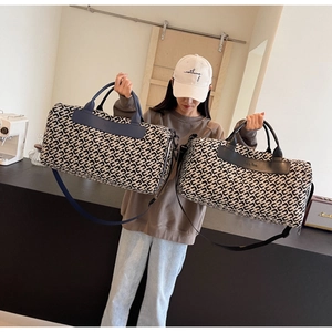 Dettaglio della grande borsa da viaggio con stampa geometrica mostrata dal modello