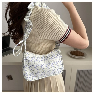 Detail of floral printed shoulder bag with ruffled strap and vintage blue flower pattern