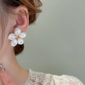 Primo piano di una modella che indossa eleganti orecchini a fiore bianchi con perle
