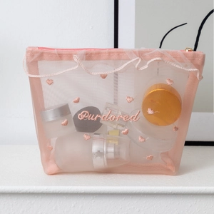 Detail of pink mesh makeup bag with heart embroidery and lace trim zipper closure