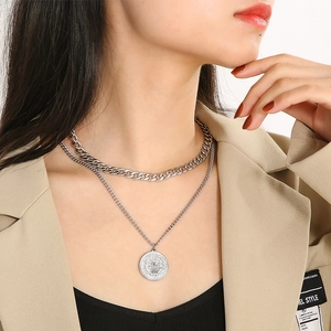 Detail of silver double layer necklace with thick Cuban chain and coin pendant charm