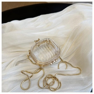Detail of transparent acrylic box bag with golden metal frame and chain strap