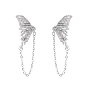 Macro detail of silver butterfly ear cuffs with pavé crystals and delicate chain tassels