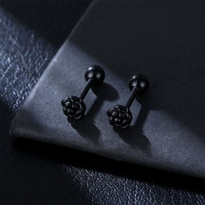 Close-up of matte black rose stud earrings with screw ball back on grey leather background