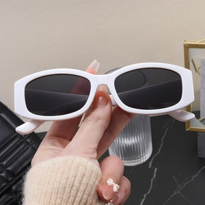 Detail of vintage white oval sunglasses featuring thick frames and dark tinted lenses