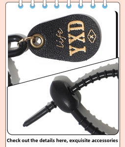 Detail of black lychee leather tag with gold embossing and bronze metal keychain ring