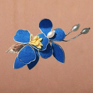 Dettaglio del fermaglio per capelli a fiore blu con pistillo giallo e perle in metallo