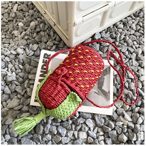 Close-up of handmade woven strawberry crossbody bag with green leaf and seed details