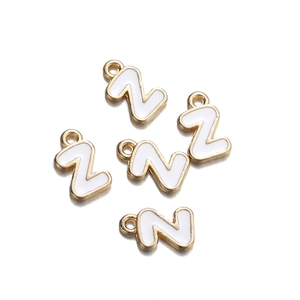 Detail of five golden metal and white enamel letter Z alphabet charms for DIY jewelry