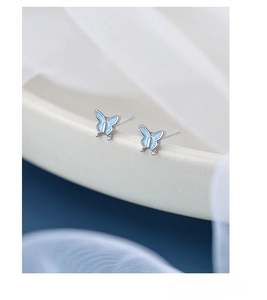 Macro shot of S925 sterling silver blue enamel butterfly stud earrings on fabric