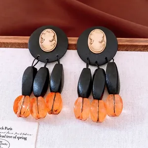 Vintage style cameo earrings with black wooden beads and orange resin tassels