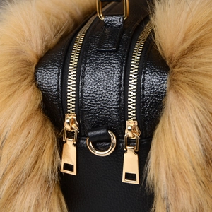 Detailed close-up of premium black pebble leather handbag with gold zippers and brown fur trim