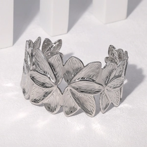 Détail d'un bracelet fleur en argent avec une finition texturée en acier brossé