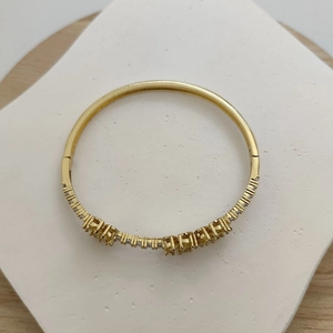 Close-up of a minimalist gold bracelet with inlaid zircon stones and delicate flower accents