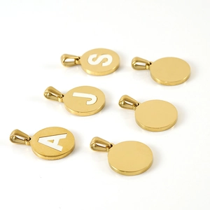 Detailed macro of 18K gold plated round shell pendants with custom letter engravings