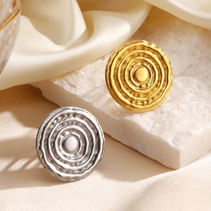 Minimalist geometric spiral rings in gold and silver finish on white stone base