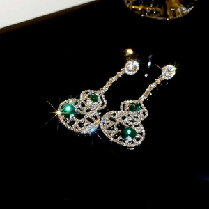 Vue macro de boucles d'oreilles gourde vert émeraude avec strass brillants et argent