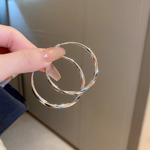 Close-up of twisted silver hoop earrings showing metallic shine and minimalist design