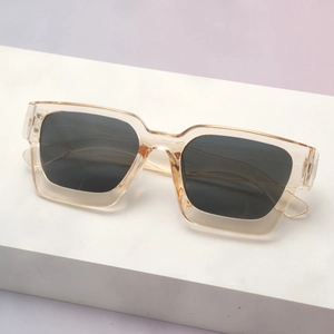 Close-up of translucent champagne thick-frame square sunglasses with dark grey lenses
