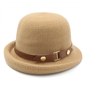 Détail d'un chapeau en tricot kaki avec lanière en cuir marron et boucle dorée