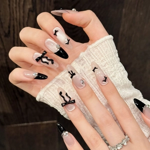 Faux ongles Cat Eye avec nœud papillon, pointes French noires et forme amande