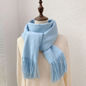 Close-up of soft blue solid cashmere-like scarf featuring elegant tassel edges on a mannequin