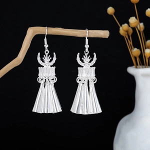 Detail of silver ethnic drop earrings with tassels hanging on a natural wooden branch