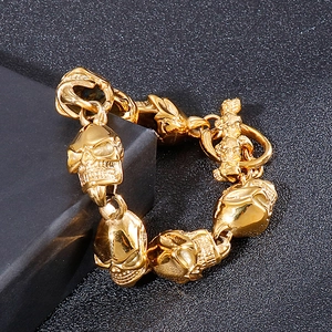 Detail of a gold skull link bracelet with OT toggle clasp on a black textured surface