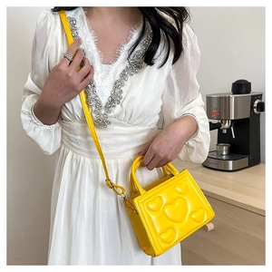 Détail d'un petit sac à main jaune avec motif cœur en relief et bandoulière