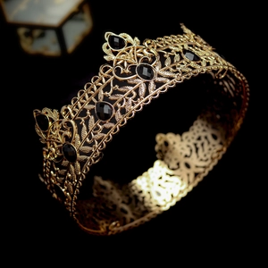 Detailed view of vintage gold baroque crown featuring black gemstones and floral patterns