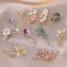 Close-up of assorted enamel flower brooches with rhinestones on beige satin fabric