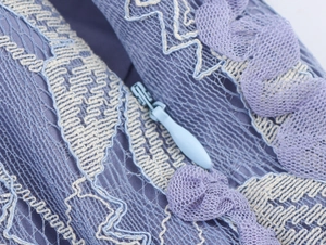 Détail du tissu en dentelle bleue avec broderie blanche et fermeture éclair invisible