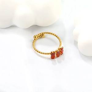 Gold twisted open ring with three red rectangular zircon stones on white background