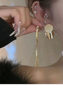 Macro view of gold sequin tassel earrings worn by a model in a minimalist style