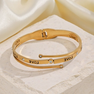 Three-layer gold stainless steel LOVE bracelet with crystal inlay on a beige stone base