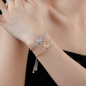 Détail d'un bracelet rivière ajustable avec breloque papillon en zircon scintillant doré